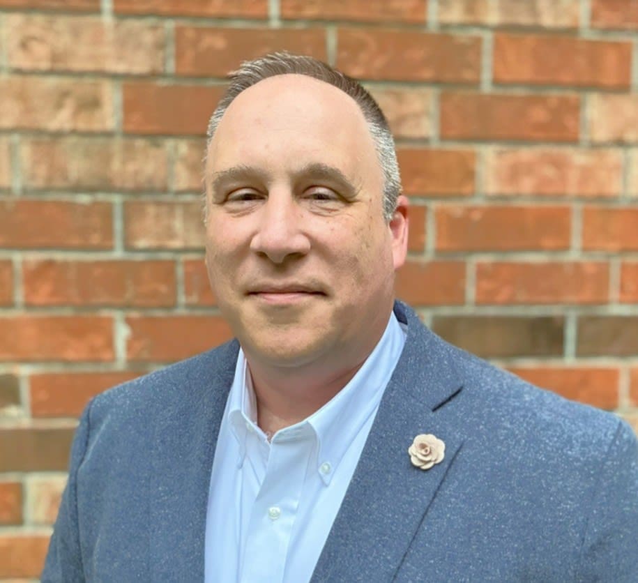 man standing in front of a brick wall